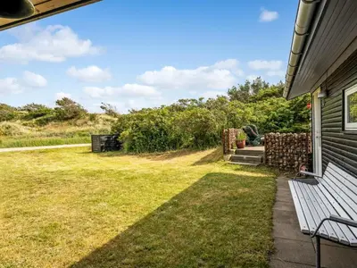 a yard with a bench next to a house at Holiday Home Selenia - 1km from the sea by Interhome in Saltum