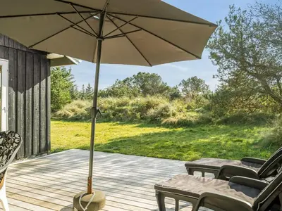 a patio with a table and an umbrella on a deck at Holiday Home Swenki - 700m from the sea by Interhome in Saltum