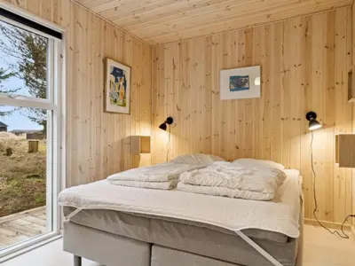 a bedroom with a bed in a wooden wall at Holiday Home Swenki - 700m from the sea by Interhome in Saltum