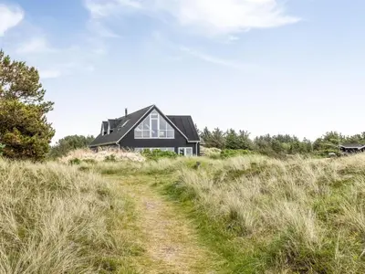 a black house on a hill with a dirt road at Holiday Home Ajvi - 900m from the sea by Interhome in Blokhus