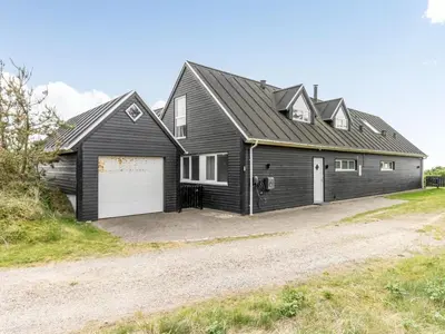 a black house with a garage on a dirt road at Holiday Home Ajvi - 900m from the sea by Interhome in Blokhus