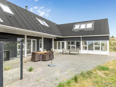 a house with a patio with a table and chairs at Holiday Home Ajvi - 900m from the sea by Interhome in Blokhus