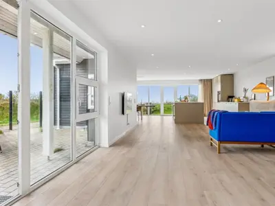 a living room with a blue couch and sliding glass doors at Holiday Home Ajvi - 900m from the sea by Interhome in Blokhus