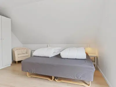 a bedroom with a bed with two pillows and a chair at Holiday Home Ajvi - 900m from the sea by Interhome in Blokhus