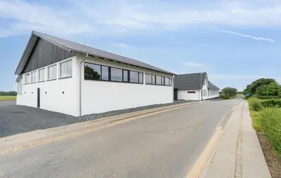 a white building with a black roof on a road at Nice Home In Spøttrup With Sauna in Spottrup