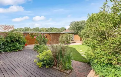 a garden with a wooden deck with plants and trees at Pet Friendly Home In Lemvig With Wifi in Lemvig