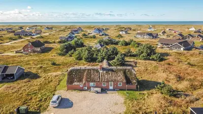 an aerial view of a farm with houses and the ocean at Cozy thatched cottage with pool by the sea - SJ450 in Harboør