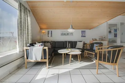a living room with a couch and a table and chairs at Cozy holiday house with pool by the sea - SJ940 in Harboør