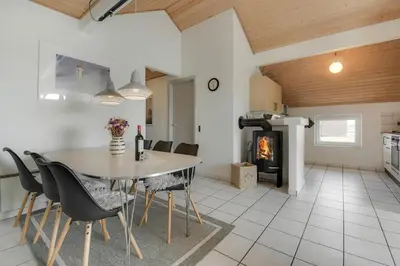 a kitchen and dining room with a table and chairs and a fireplace at Cozy holiday house with pool by the sea - SJ940 in Harboør