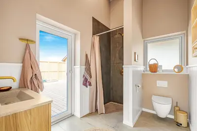 a bathroom with a shower and a toilet and a door at Uniquely located wooden cottage by the sea - SJ1 in Harboør