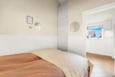 a white bedroom with a bed and a window at Uniquely located wooden cottage by the sea - SJ1 in Harboør