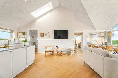 a kitchen and living room with a couch and a table at Uniquely located wooden cottage by the sea - SJ1 in Harboør