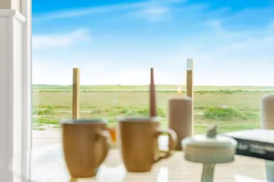 a group of coffee cups sitting on a window sill at Uniquely located wooden cottage by the sea - SJ1 in Harboør