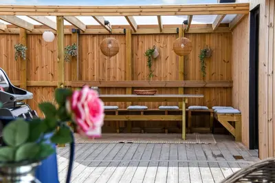 a patio with a bench and baskets on a wooden fence at Uniquely located wooden cottage by the sea - SJ1 in Harboør