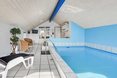 a large swimming pool with blue walls at Holiday home with spa and pool by the sea - SJ670 in Harboør