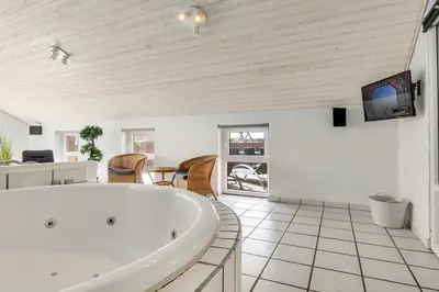 a large bathroom with a tub and a tv at Holiday home with spa and pool by the sea - SJ670 in Harboør