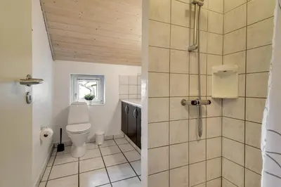 a bathroom with a toilet and a shower at Holiday home with spa and pool by the sea - SJ670 in Harboør