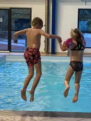 two young people jumping into a swimming pool at Himmerland camping & Feriecenter in Års