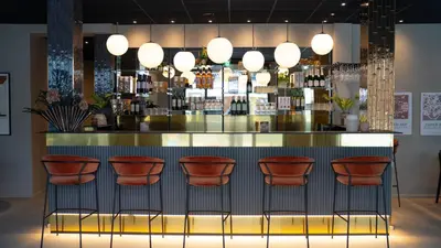 a bar with red stools in a room at Hotel Nørreport in Holstebro