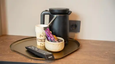 a coffee pot with a cup and a remote control at Hotel Nørreport in Holstebro