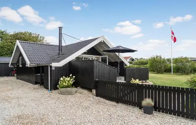 a house with a black fence and an umbrella at Cozy Home In Vestervig With Wifi in Vestervig