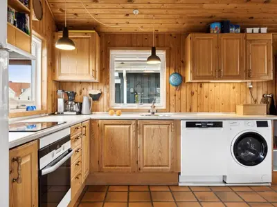 a kitchen with wooden cabinets and a washer and dryer at Holiday Home Dolores - 200m from the sea by Interhome in Torsted