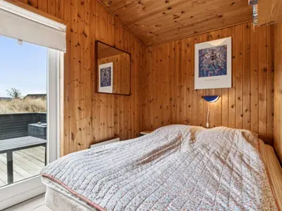 a bedroom with wooden walls and a bed with a window at Holiday Home Dolores - 200m from the sea by Interhome in Torsted