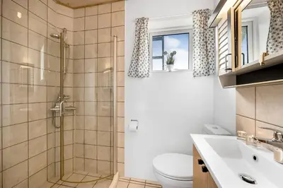 a bathroom with a shower and a toilet and a sink at Nyd den skønne natur ved hav og fjord in Thyborøn
