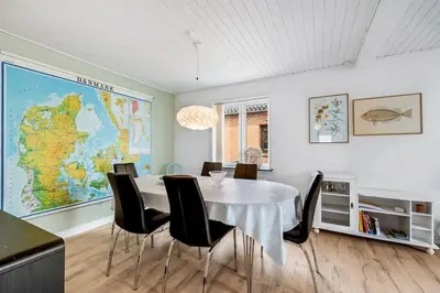 a dining room with a table and a map on the wall at Nyd den skønne natur ved hav og fjord in Thyborøn