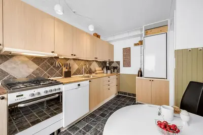 a kitchen with wooden cabinets and a white stove top oven at Nyd den skønne natur ved hav og fjord in Thyborøn