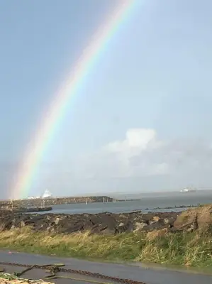 a rainbow in the sky over a body of water at Nyd den skønne natur ved hav og fjord in Thyborøn