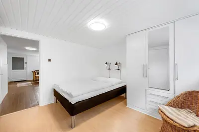 a white room with a bed and a chair at Nyd den skønne natur ved hav og fjord in Thyborøn
