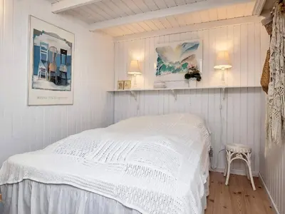 a white bedroom with a bed and a chair at 4 star holiday home in Blokhus-By Traum in Blokhus