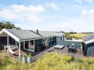 a blue house with a deck on the beach at 4 star holiday home in Blokhus-By Traum in Blokhus