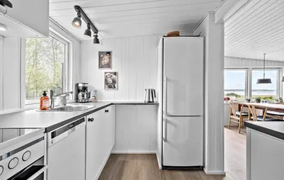 a white kitchen with a refrigerator and a table at 2 Bedroom Awesome Home In Højslev in Højslev