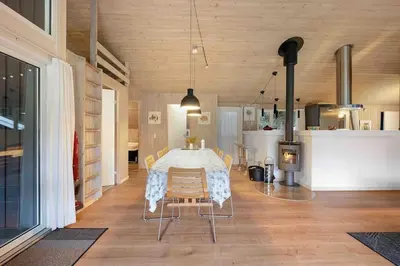 a dining room with a table and chairs and a kitchen at Pool summerhouse in Saltum near Blokhus in Saltum