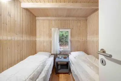 two beds in a small room with a window at Pool summerhouse in Saltum near Blokhus in Saltum