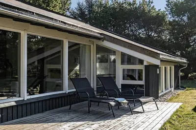 a screened in porch with chairs on a deck at Pool summerhouse in Saltum near Blokhus in Saltum