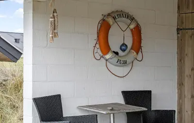 a table and chairs against a white wall with a life preserver at Gorgeous Home In Thisted in Thisted