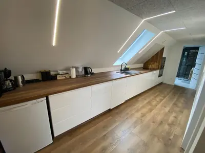a kitchen with white cabinets and a wooden floor at Sunny apartment in Åbybro