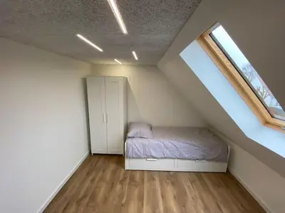 a attic bedroom with a bed and a window at Sunny apartment in Åbybro