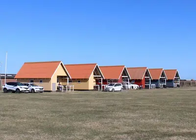 a row of buildings with cars parked in a field at Camping Vesterhav in Harboør