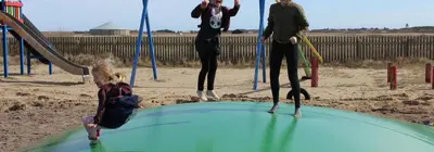 a group of people playing on a playground at Camping Vesterhav in Harboør