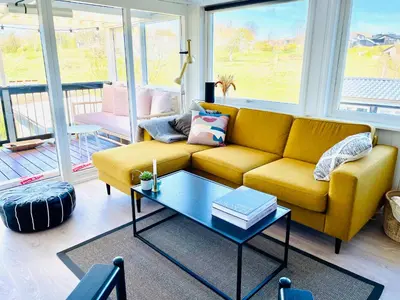 a living room with a yellow couch and a table at Dejligt sommerhus med udsigt over fjorden in Løgstrup