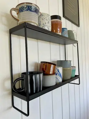 a black shelf with bowls and cups on it at Dejligt sommerhus med udsigt over fjorden in Løgstrup