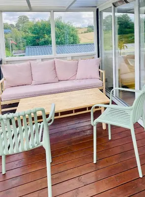 a couch and two chairs on a porch at Dejligt sommerhus med udsigt over fjorden in Løgstrup