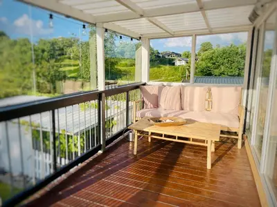 a screened in porch with a couch and a coffee table at Dejligt sommerhus med udsigt over fjorden in Løgstrup