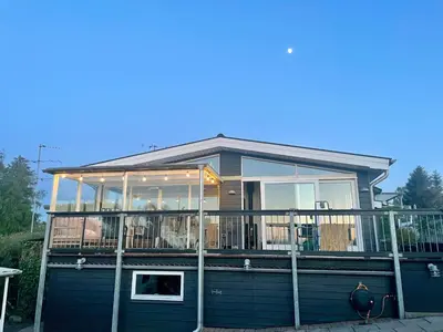 a house with a deck with a railing at Dejligt sommerhus med udsigt over fjorden in Løgstrup