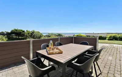 a table with chairs and a bottle of wine on a patio at Gorgeous Home In Øster Assels With Wifi in Øster Assels