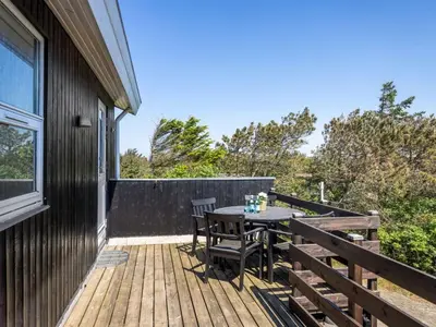 a wooden deck with a table and chairs on it at Holiday Home Letje - 500m from the sea by Interhome in Løkken